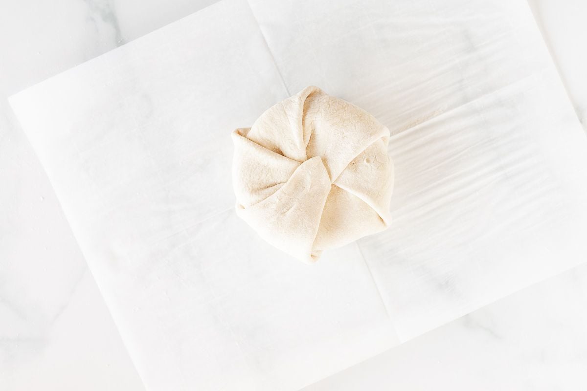 Baked brie puff pastry round on a sheet of parchment