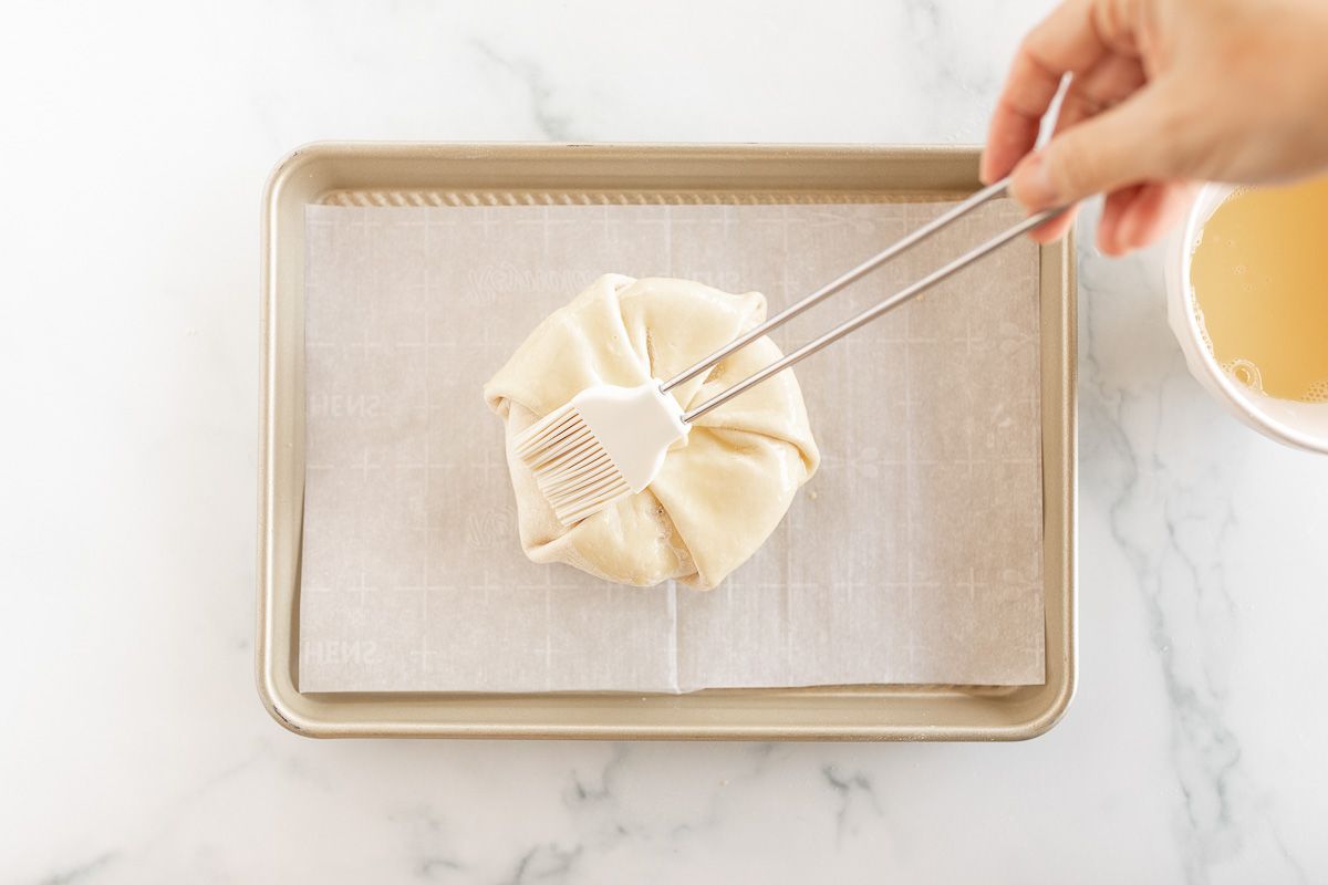 Baked brie in puff pastry getting an egg wash prior to baking
