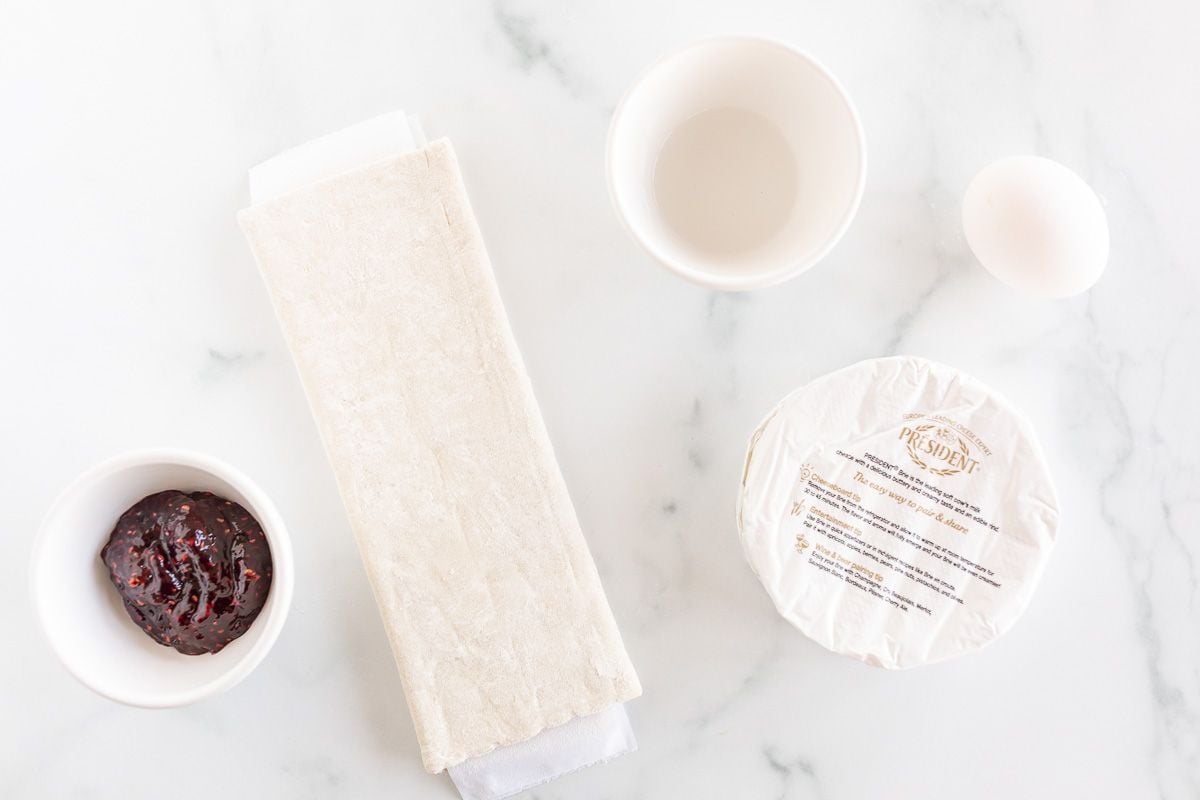 ingredients for baked brie puff pastry on a white marble surface