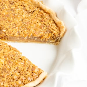 A decadent caramel pecan pie with a slice taken out of it.