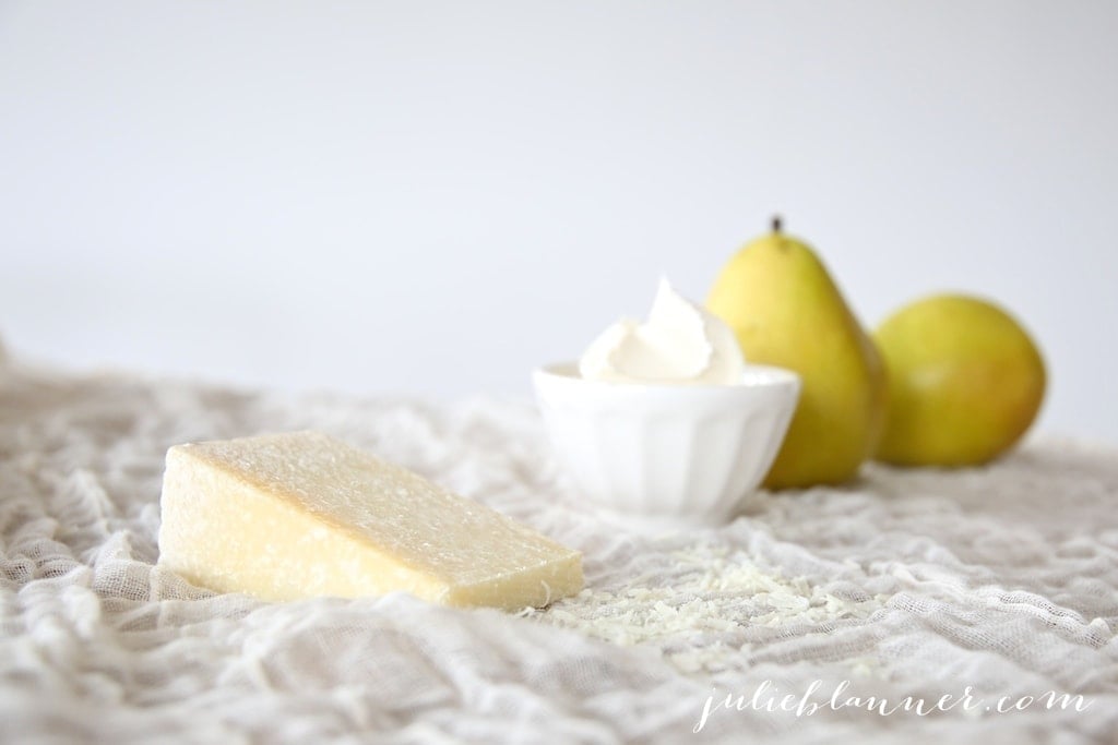 a chunk of cheese, a bowl of mascarpone and pears in the background.