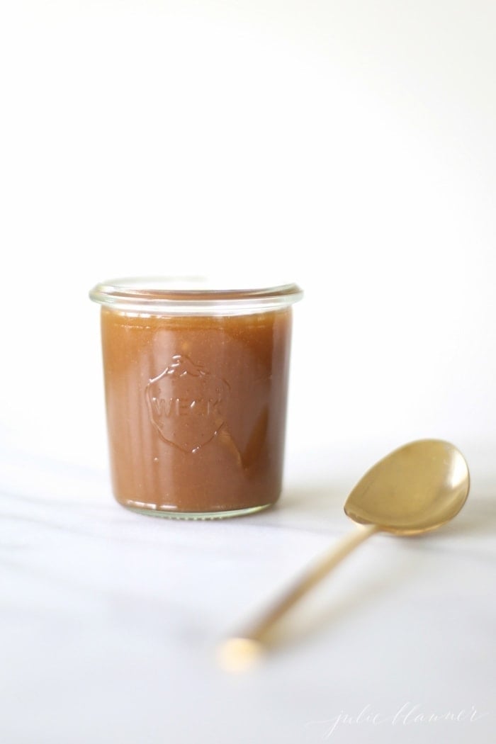 Salted Caramel Sauce in a glass jar next to a spoon