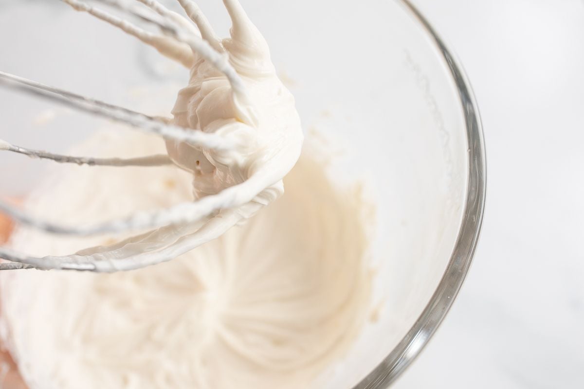 A glass bowl of a stand mixer, filled with icing