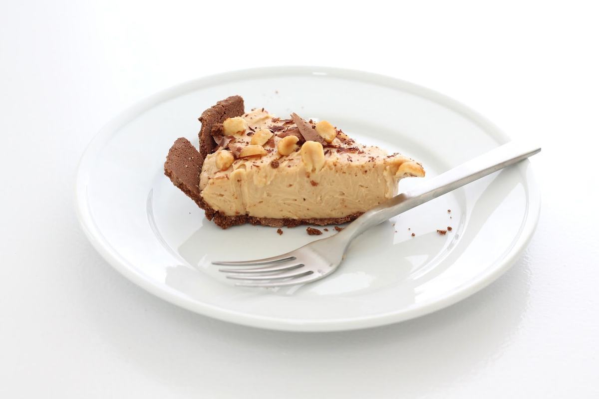 slice of peanut butter and chocolate cheesecake on white plate with fork