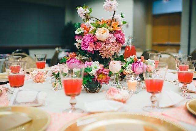 A close up of a pink, orange, green, and purple flowers with a raspberry cocktail to the side.