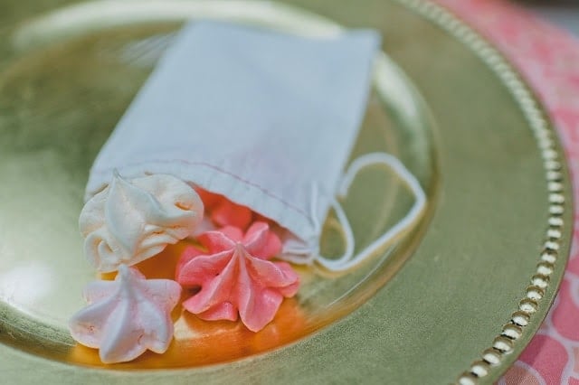 A small white pouch with meringue cookies coming out of it on a gold plate