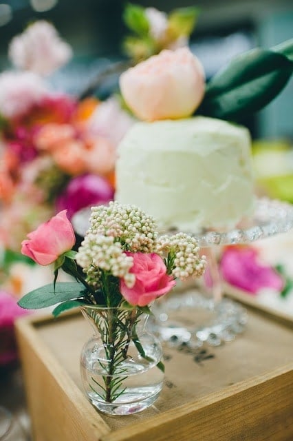 A close up of flowers with a cake in the background