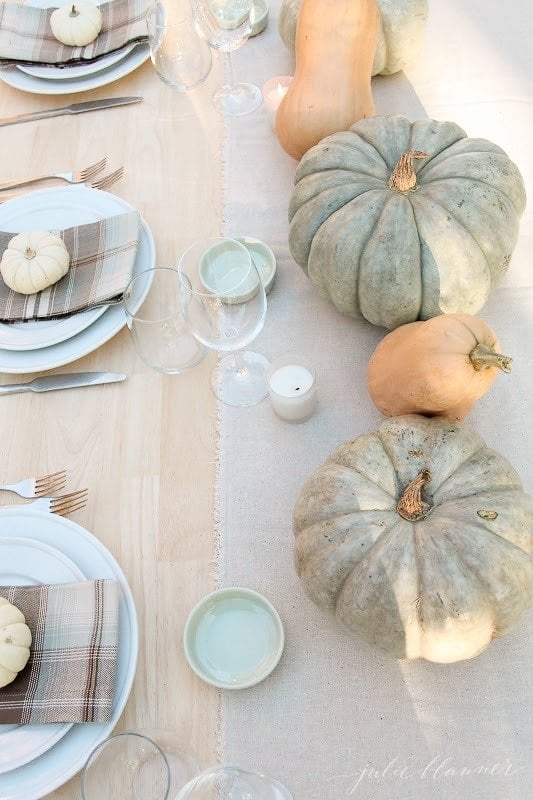 Various pumpkins and gourds on a set Thanksgiving table.