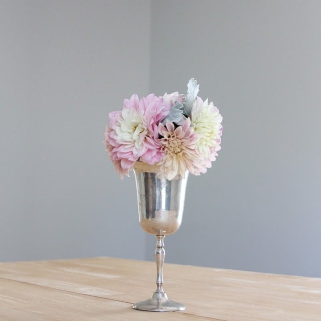 A silver vase with pink and white flowers on a table.