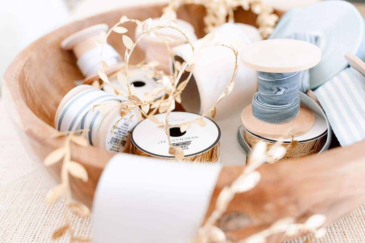 Blue and gold ribbons for Christmas gift wrapping ideas in a wooden bowl.