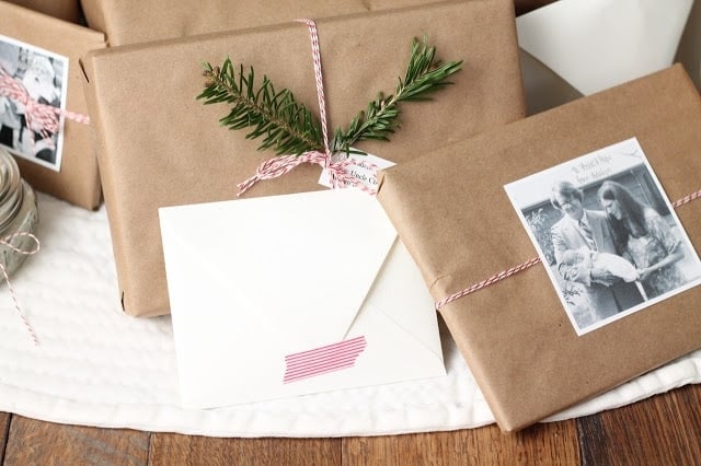 Brown kraft paper wrapped presents tied with baker\'s twine and decorated with old family photos and holiday greenery.