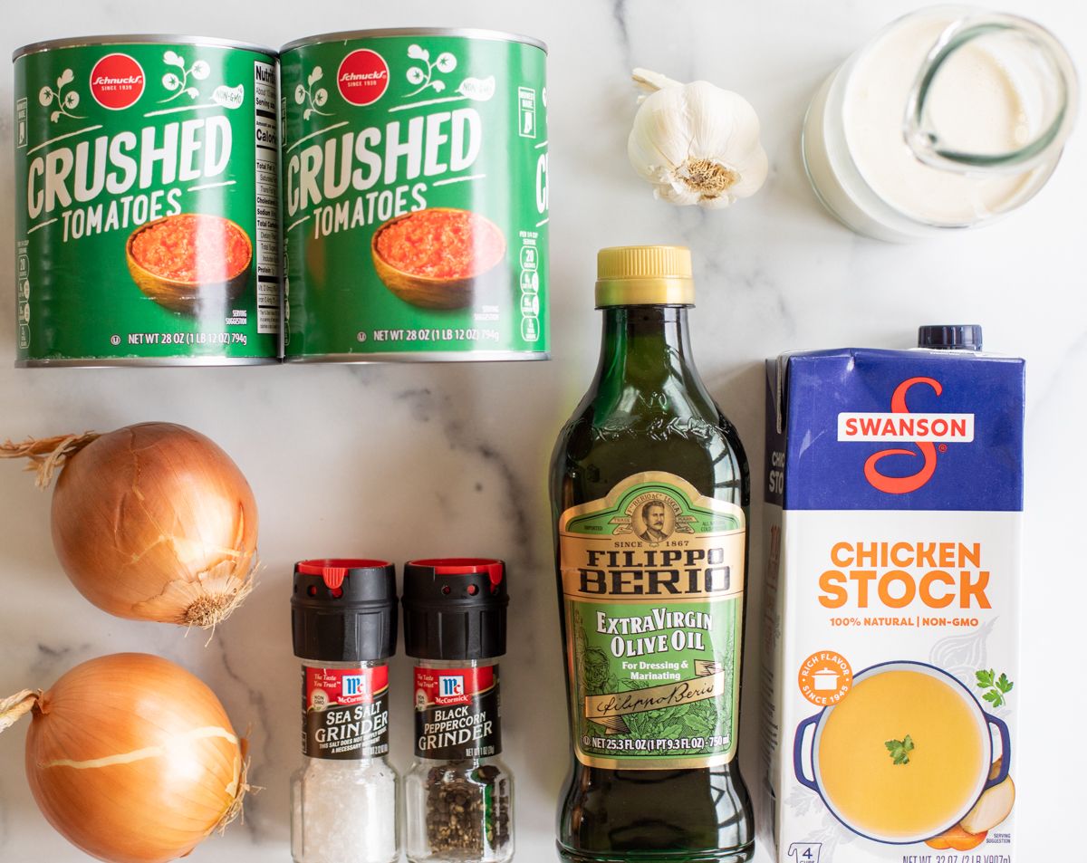 Ingredients for creamy tomato soup on a marble countertop.