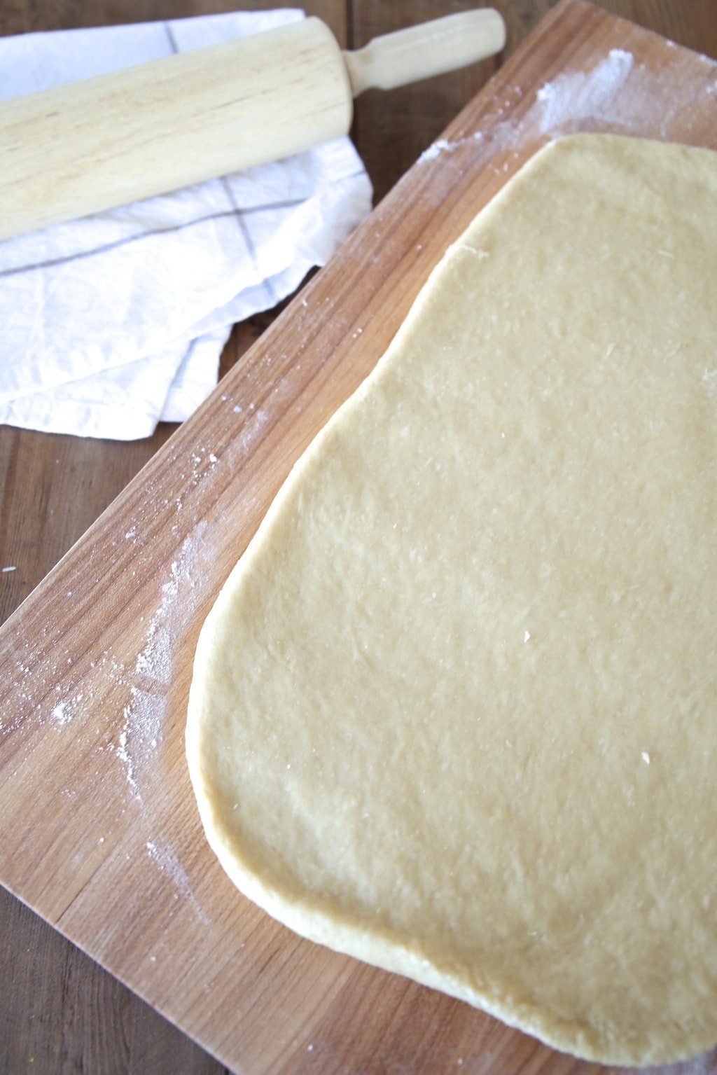 Dough rolled out on a wooden chopping board