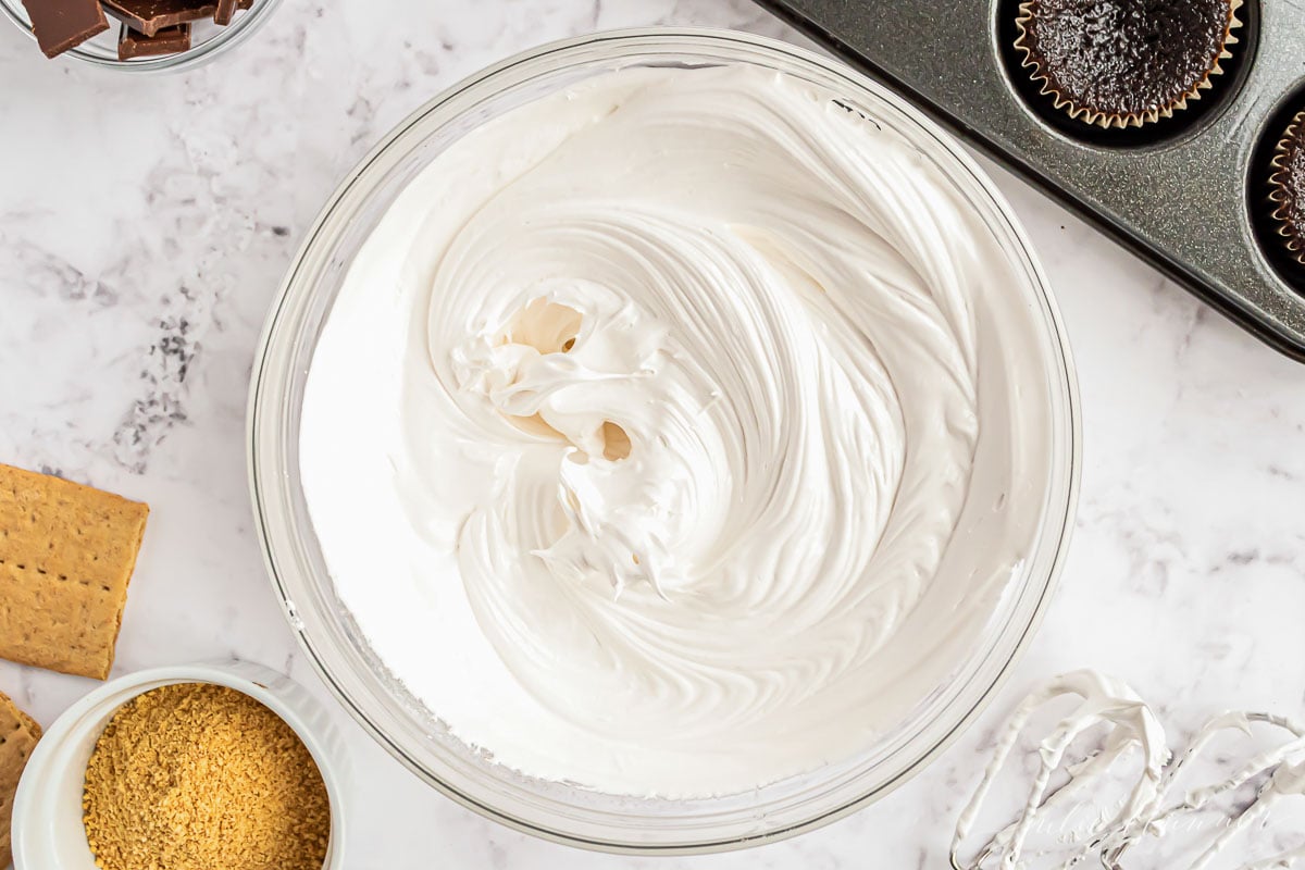 A clear glass bowl full of whipped marshmallow icing.