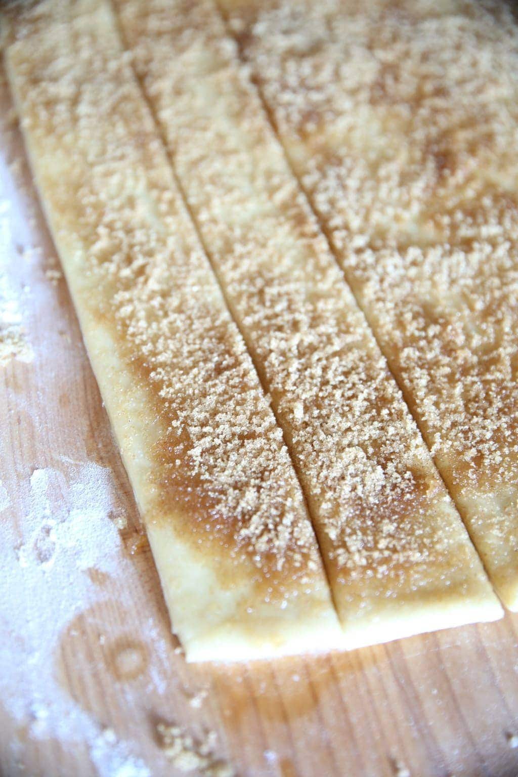 Sugar and cinnamon sprinkled on strips of dough