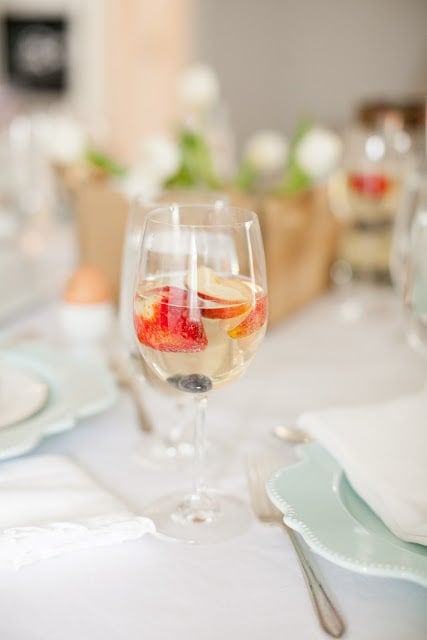 A champagne punch peach cocktail in a glass with fresh fruit