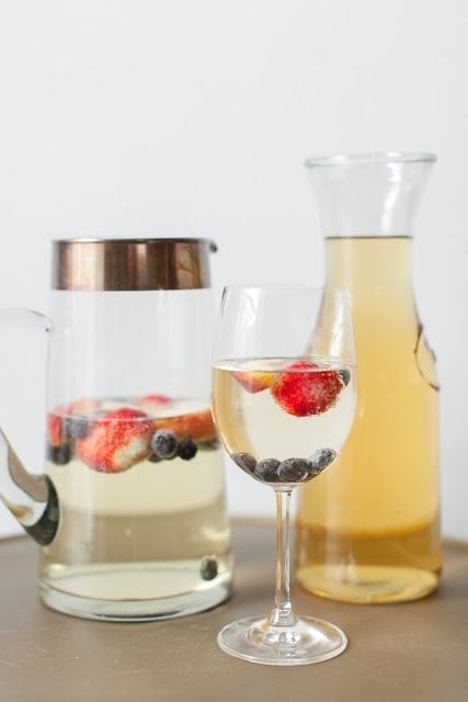 The champagne brunch punch in a glass next to two jugs