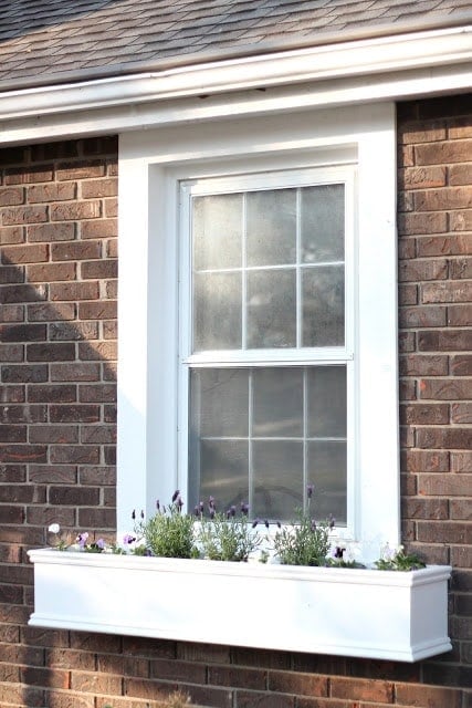 DIY wood window boxes on the front of a house filled with spring flowers