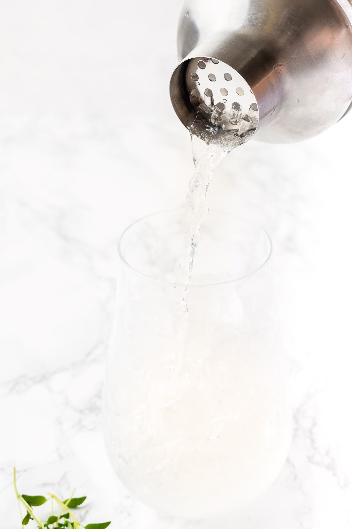 A vodka lemonade cocktail being poured in a clear glass over ice