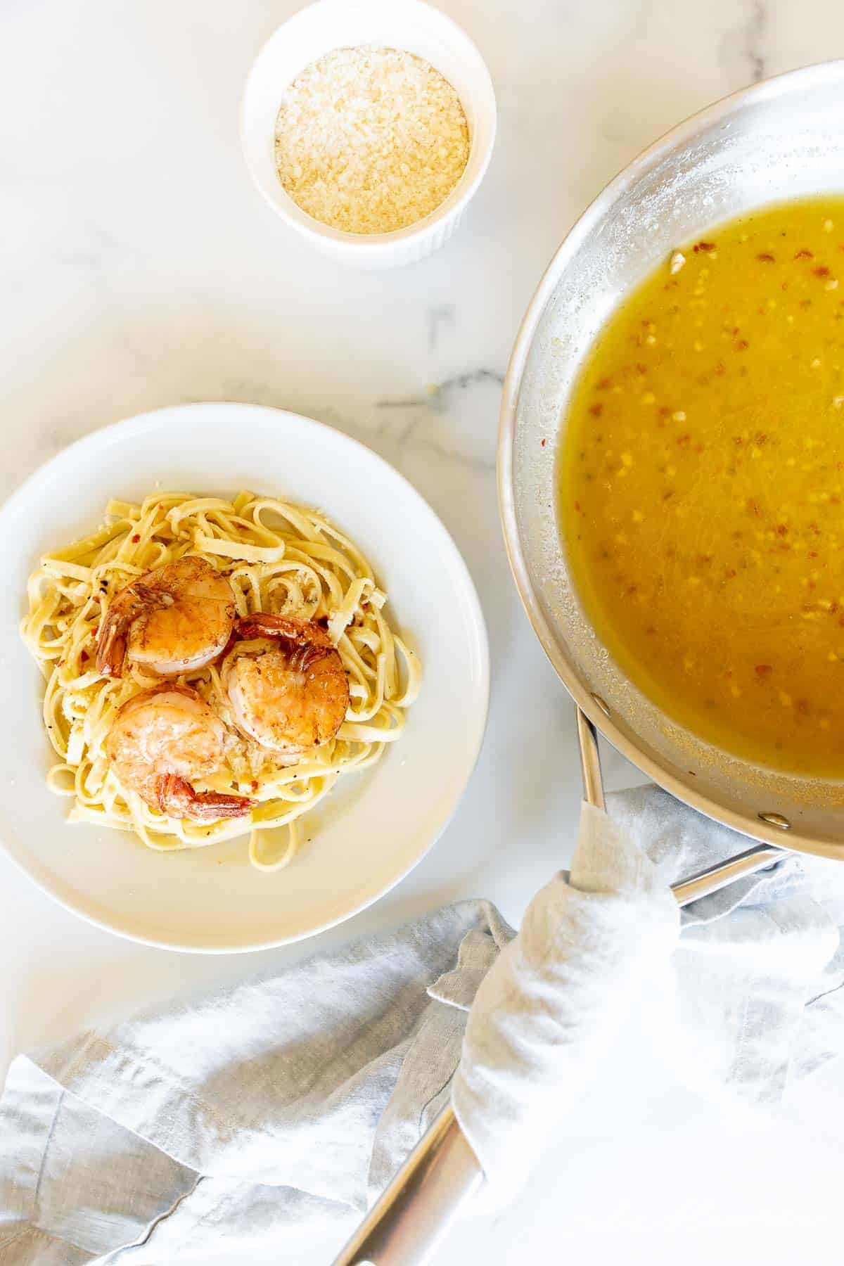 pasta with shrimp next to wine sauce in saucepan