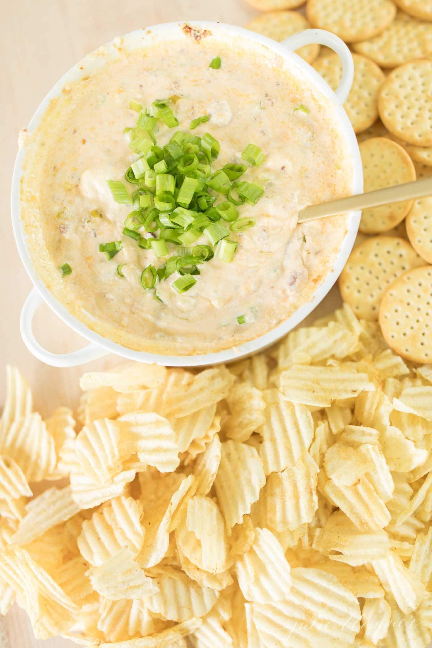 Bacon cheese dip in a white bowl next to chips