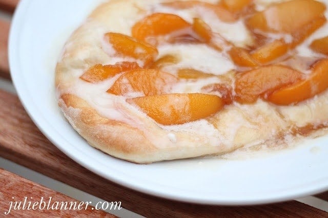 A dessert pizza topped with sliced peaches