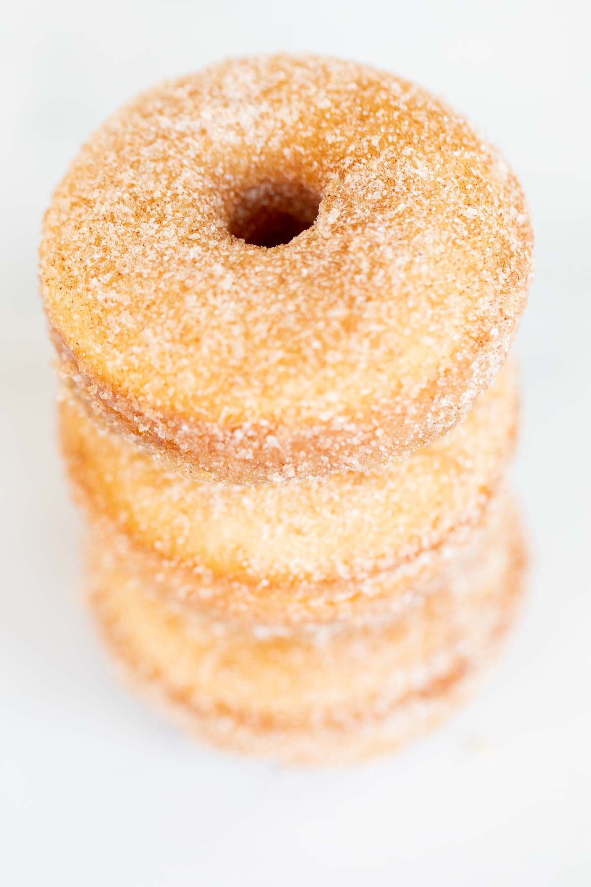 Cinnamon sugar donuts stacked on a marble countertop.