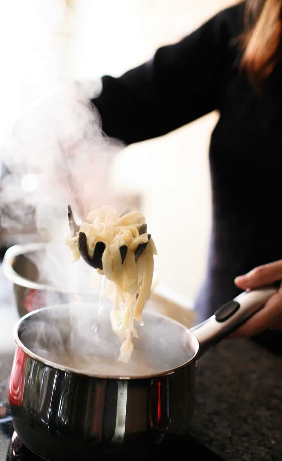 straining homemade pasta noodles with ladle