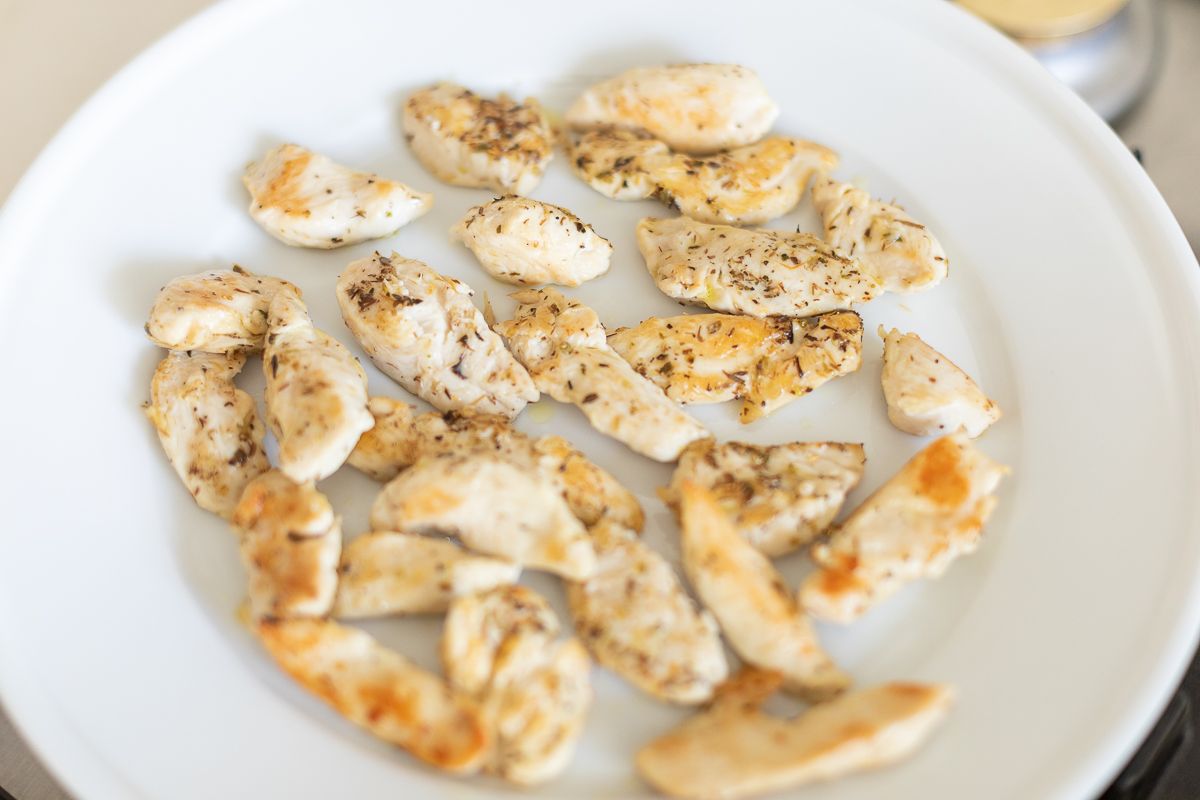 Cooked chicken tenders on a white plate.