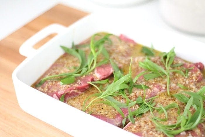 Fresh tarragon on top of the marinatng steak