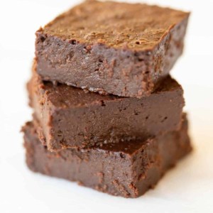 White surface with a stack of three dark chocolate brownies.