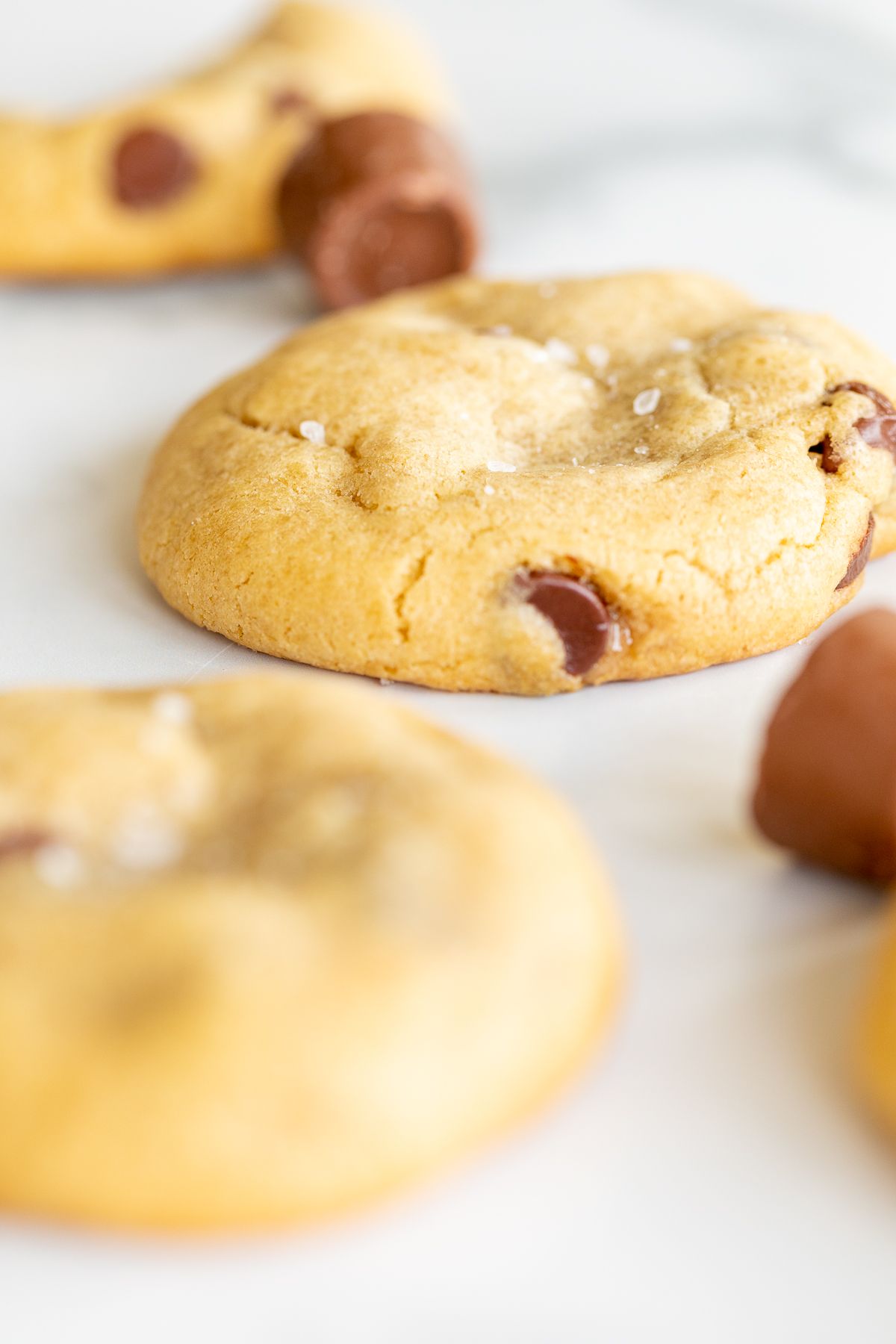 Salted caramel chocolate chip cookies on a marble countertop, surrounded by chocolate rolos.