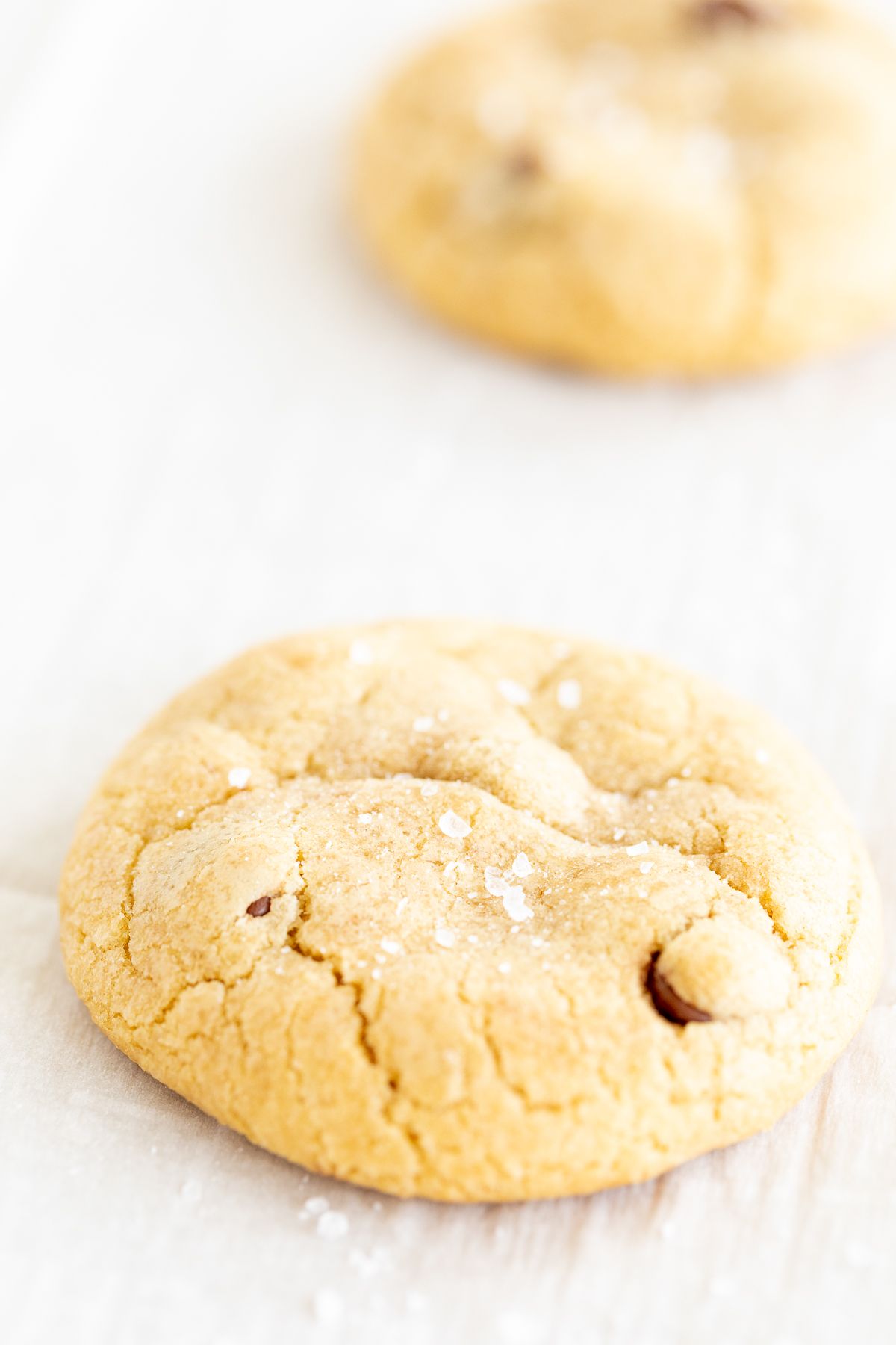 Salted caramel chocolate chip cookies on a parchment lined baking sheet.