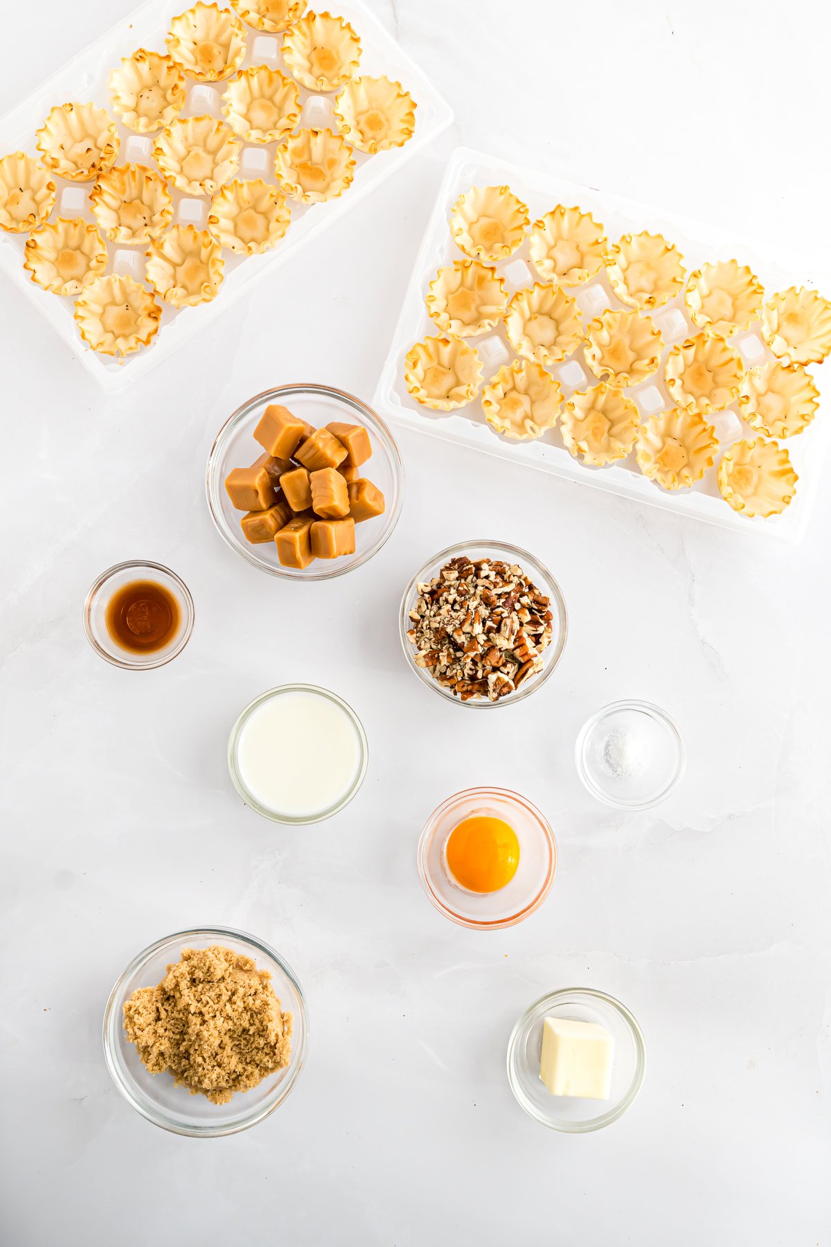 A white table with a variety of Mini Pecan Pie bites and caramel pecan pie.