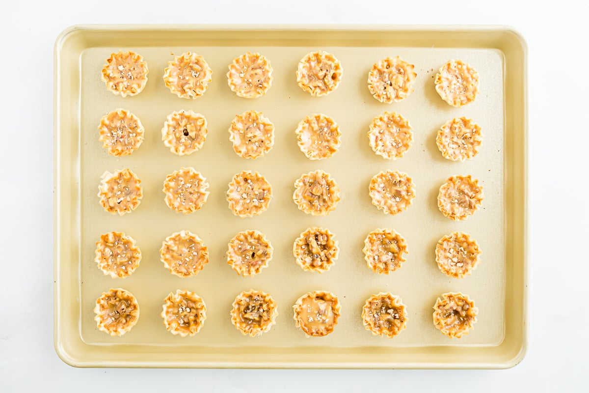 A baking sheet with a tray of mini pecan pie bites on it.