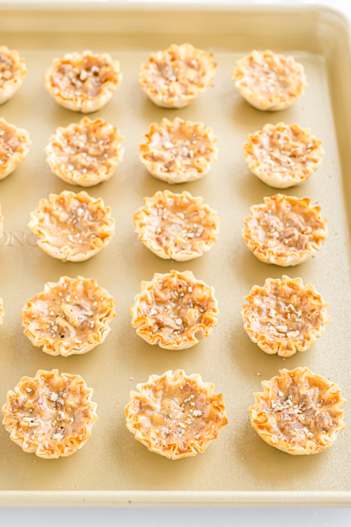 A tray of mini pecan pie bites on a baking sheet.