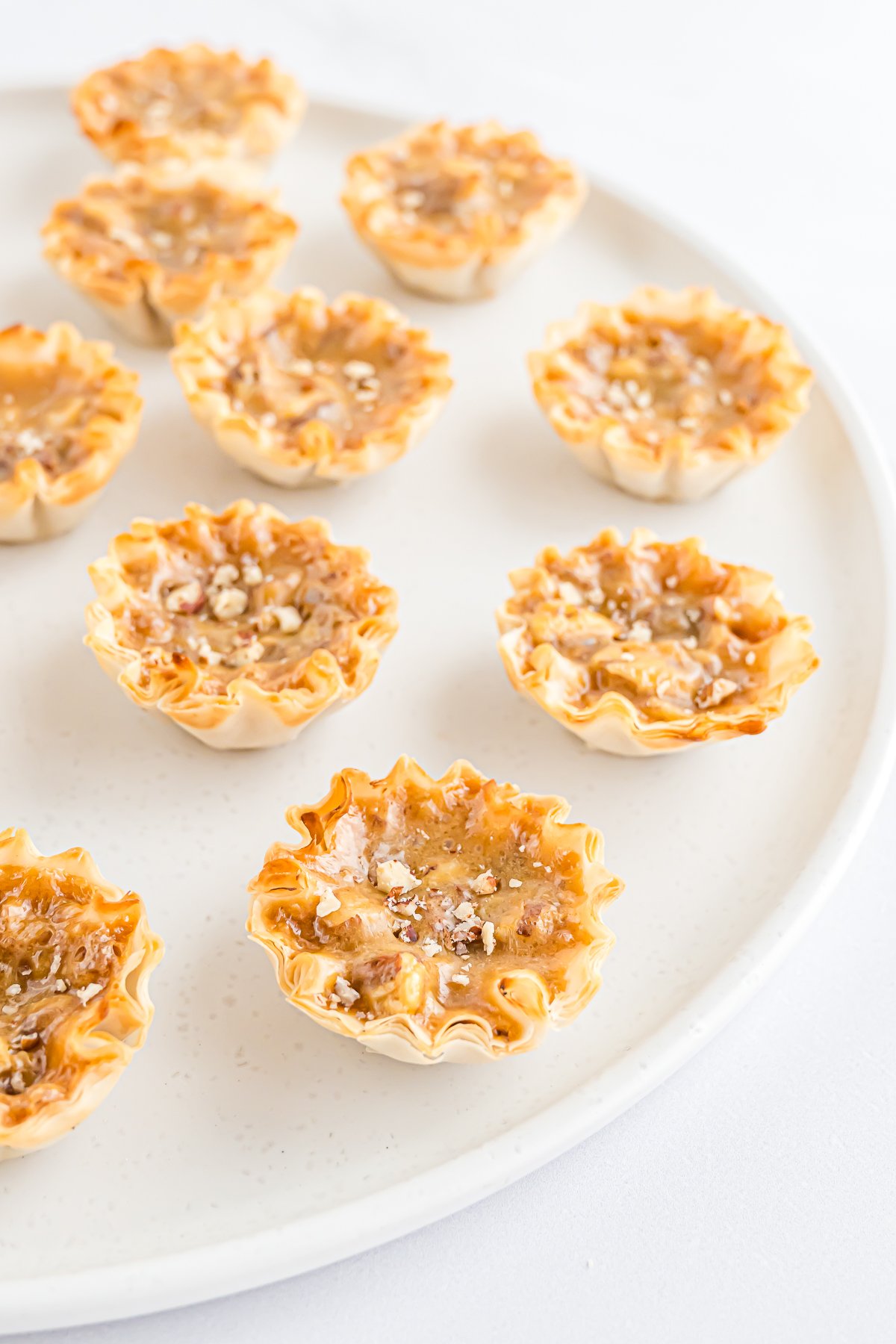 A white plate with mini pecan pie bites on it.