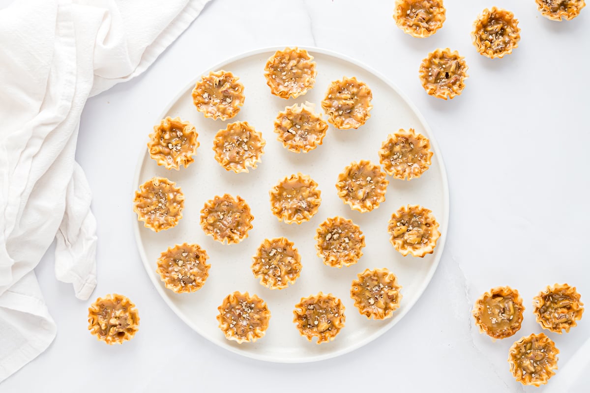 A plate with a white napkin and a plate full of mini pecan pies.