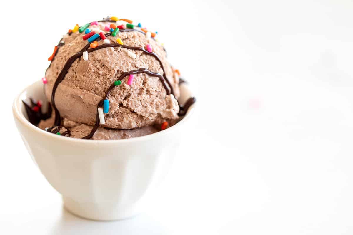 chocolate snow ice cream topped with chocolate and sprinkles in white bowl
