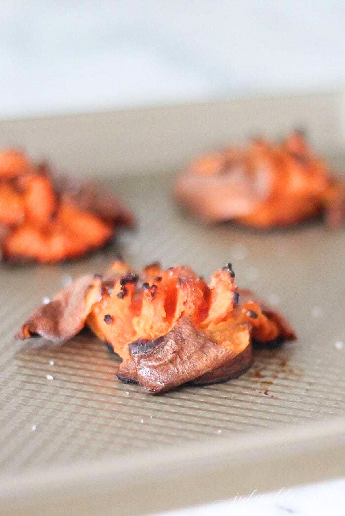 Roasted smashed sweet potatoes on a baking sheet.