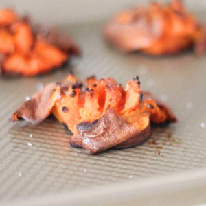 Smashed sweet potatoes roasted on a baking sheet.