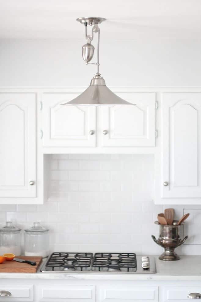 A silver light fixture in a white low budget kitchen renovation.