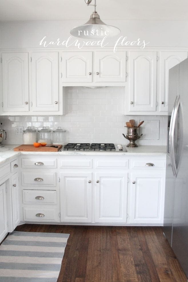 A white kitchen with hand scraped wood floors.