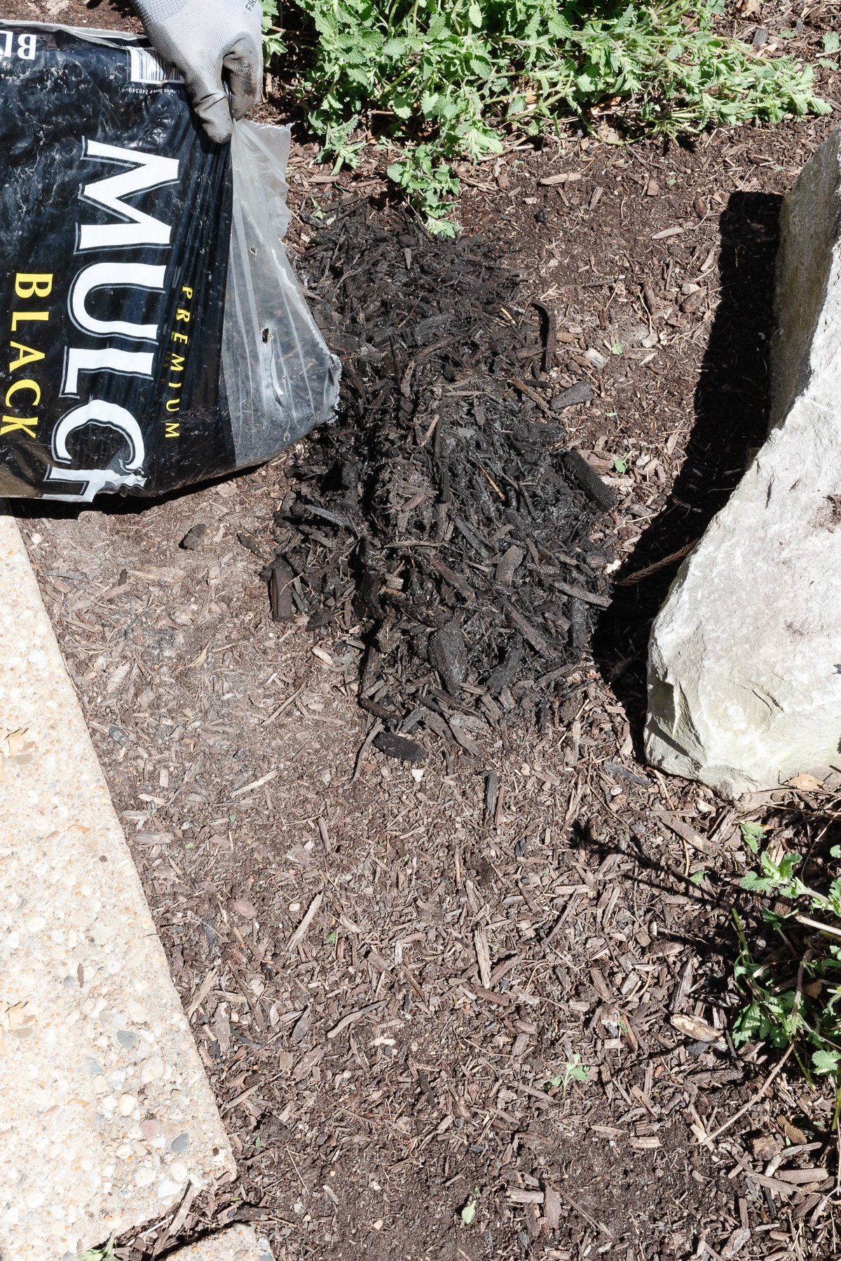 Dark mulch being added to a flower bed.