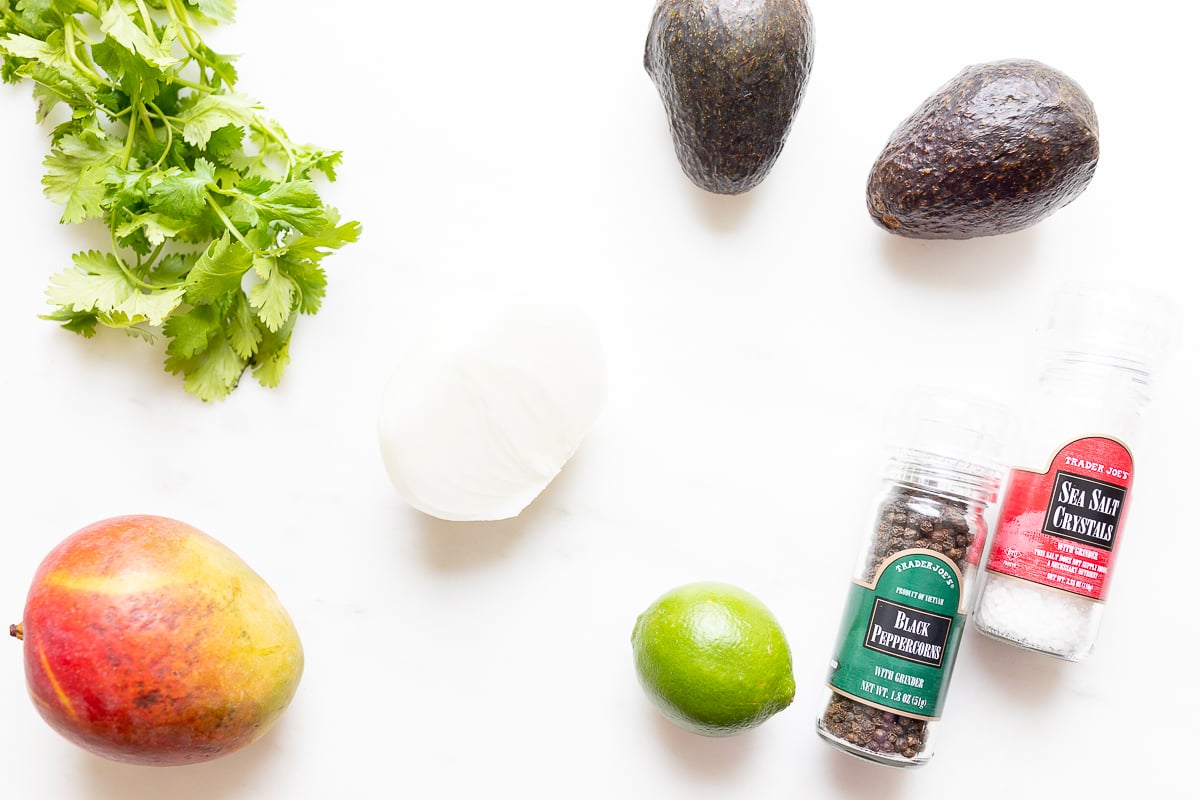 Ingredients for a mango guacamole recipe on a white countertop.