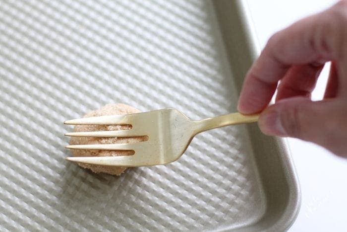 A fork pressing down on the cookie dough