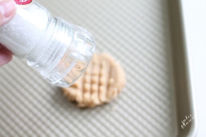 Salt being sprinkled on an uncooked peanut butter cookie