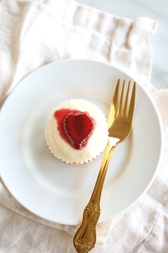 An individual cheesecake on a white plate with a fork