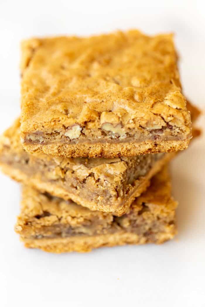 stack of three homemade pecan pie bars on white surface