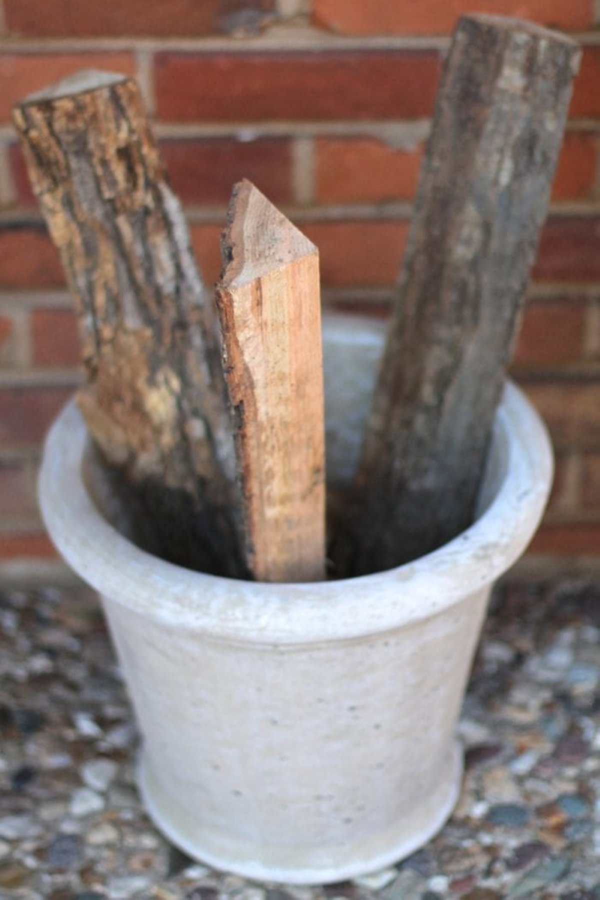 A porch planter with three pieces of firewood inside for a winter planter for front porch